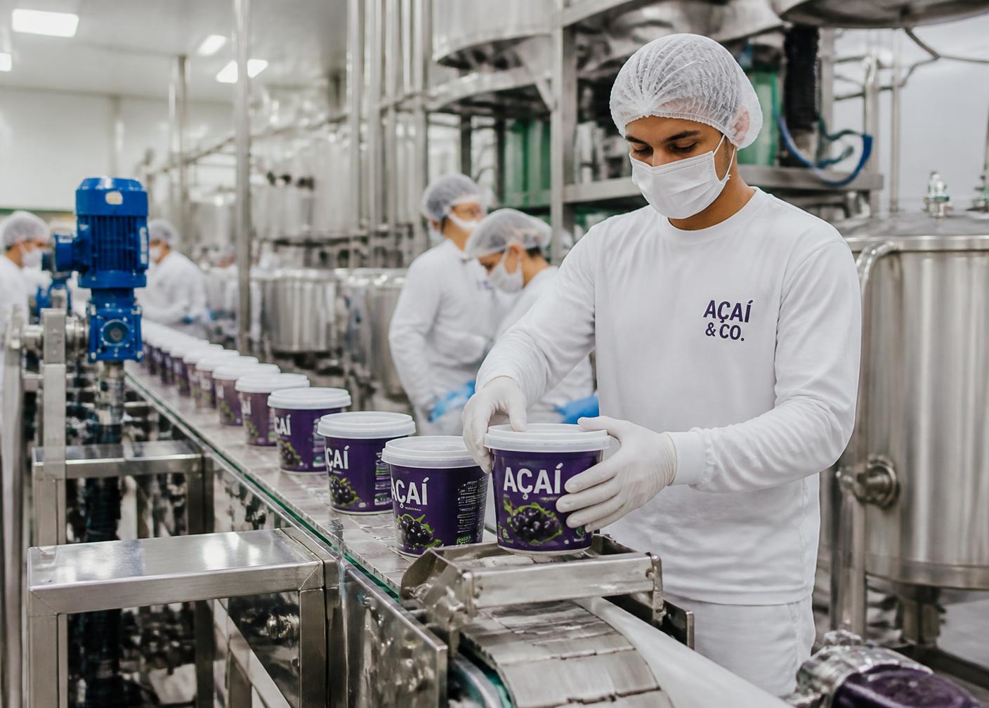 Equipe da produção envasando potes de açaí na fábrica